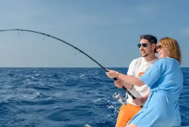Happy tourist catching big Red Sea fish during private fishing tour