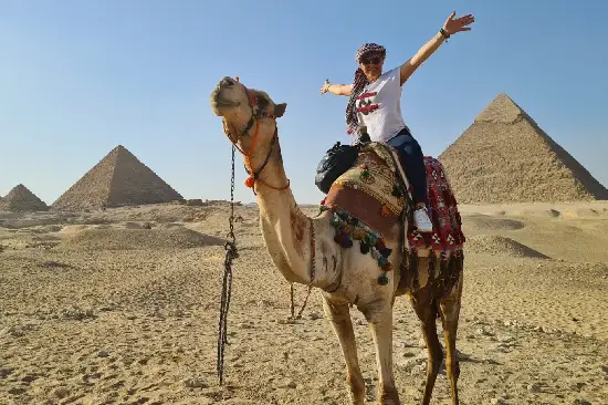 Touristin beim Kamelreiten vor den Pyramiden von Gizeh Kairo.