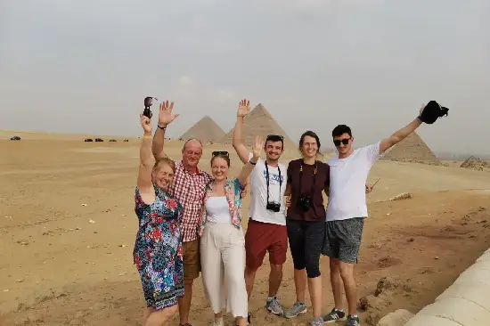 Glückliche Touristengruppe winkt vor den Pyramiden von Gizeh in Kairo.